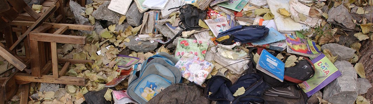 Children's clothes scattered amongst the debris of a collapsed building