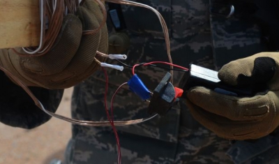A soldier examines components of an improvised explosive device.