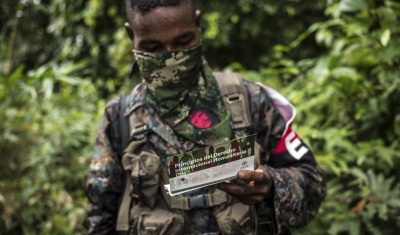 Colombia, Chocó Department. A member of the ELN armed group is reading an ICRC handout about the principles of the international humanitarian right and the obligation to respect the lives of the civilian population, health personnel, and the sick or wound