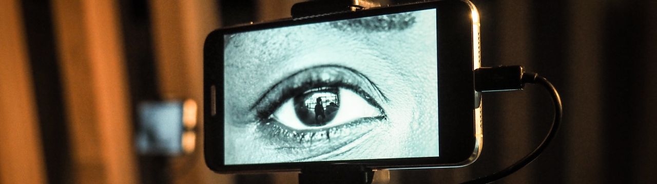 Photo of an art installation: The installation is made up of robots with eyes. When a user begins to interact with their smartphone, one of the robot eyes opens and begins looking around the room. When the interaction is over, the eye closes again.