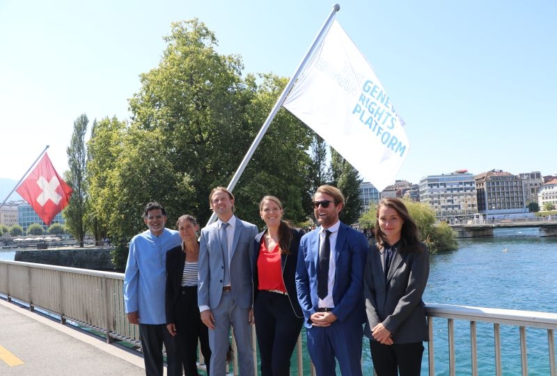 The Geneva Human Rights Platform team on the Mont-Blanc bridge with flags of the platform behind