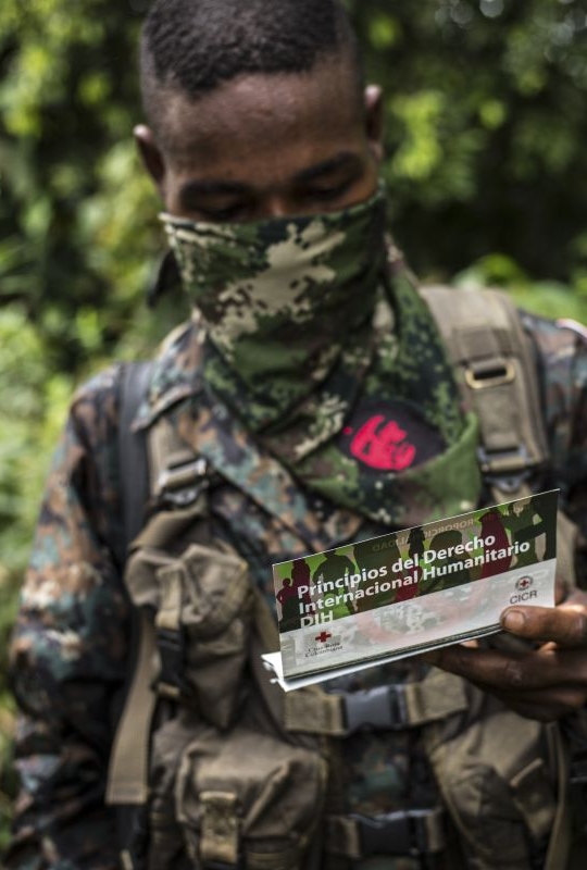 Member of an armed groupo holding an ICRC leaflet on IHL