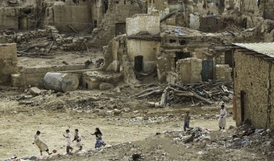  Yemen, Saada. A group of children play football against a backdrop of destroyed houses. 